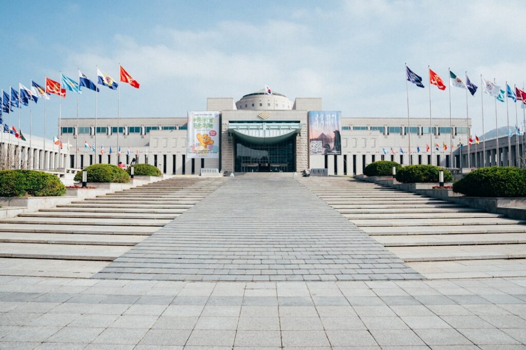 A grand building and pathway with flags.